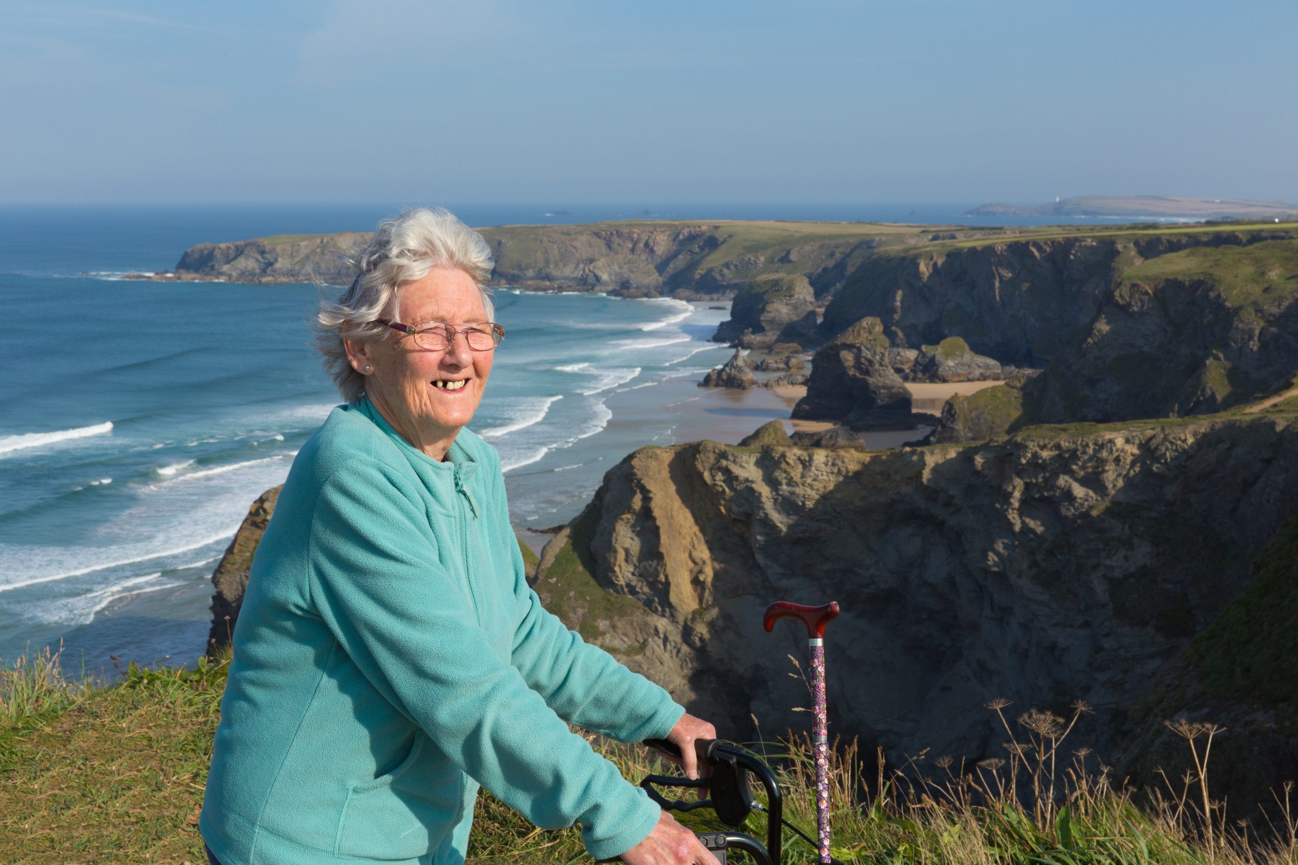 Happy elderly female pensioner by coast scene Cornwall England UK